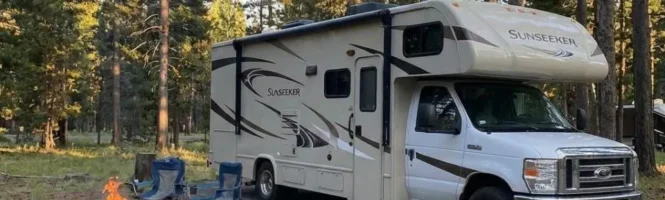 Class A RV with two chairs and a bonefire