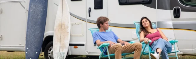 A man and a woman sitting together with an RV behind them discussing how long are rv loans
